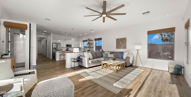 living area featuring arched walkways, visible vents, and light wood-style floors