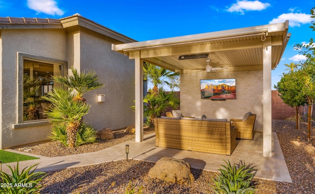 view of patio with an outdoor living space, ceiling fan, and fence