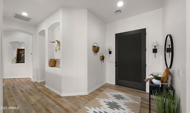 entryway with wood finished floors, visible vents, and baseboards