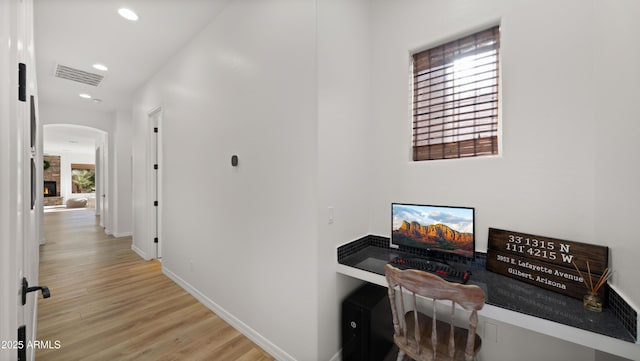 hall featuring visible vents, recessed lighting, arched walkways, light wood finished floors, and baseboards