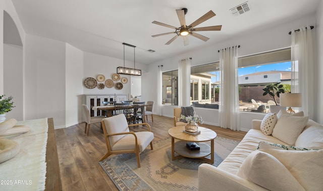 living room with wood finished floors, a healthy amount of sunlight, visible vents, and baseboards