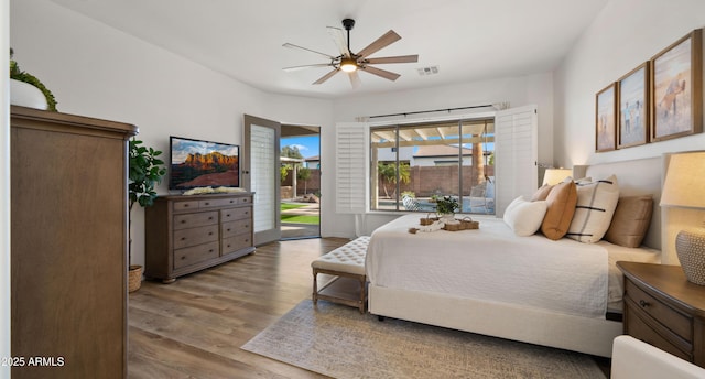 bedroom featuring access to outside, wood finished floors, visible vents, and ceiling fan