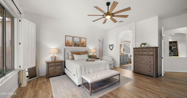 bedroom with visible vents, arched walkways, baseboards, and wood finished floors