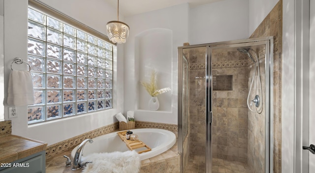 full bathroom with an inviting chandelier, a shower stall, and a garden tub