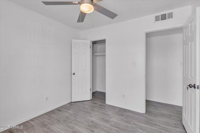 unfurnished bedroom featuring ceiling fan, baseboards, wood finished floors, visible vents, and a closet