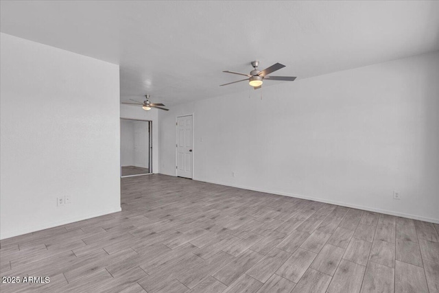 spare room featuring a ceiling fan, baseboards, and light wood-type flooring