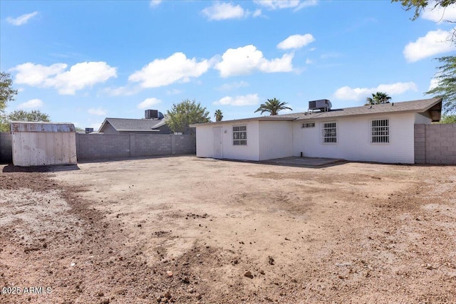 back of house featuring a storage unit, a fenced backyard, and an outbuilding