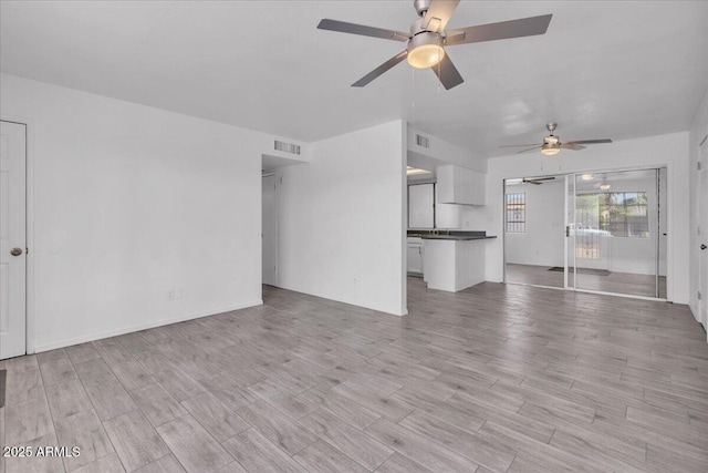 unfurnished living room with a ceiling fan, visible vents, and light wood finished floors