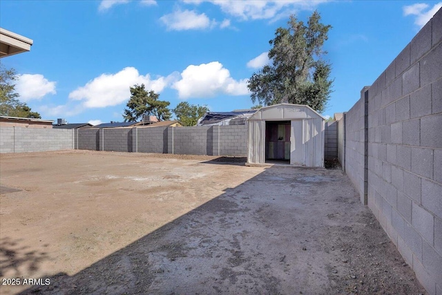 view of yard with an outdoor structure, a fenced backyard, and a storage shed