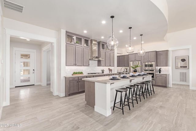 3940 Rolling Stock Way, Wickenburg, AZ 85390 - kitchen featuring wall chimney range hood, visible vents, a kitchen breakfast bar, and appliances with stainless steel finishes