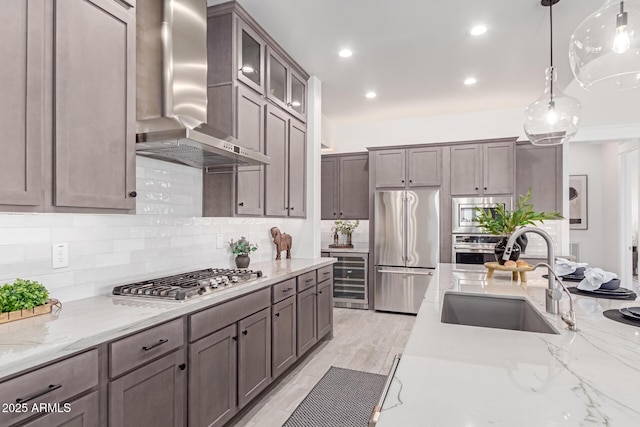 3940 Rolling Stock Way, Wickenburg, AZ 85390 - kitchen with wall chimney exhaust hood, light stone counters, a sink, stainless steel appliances, and decorative backsplash