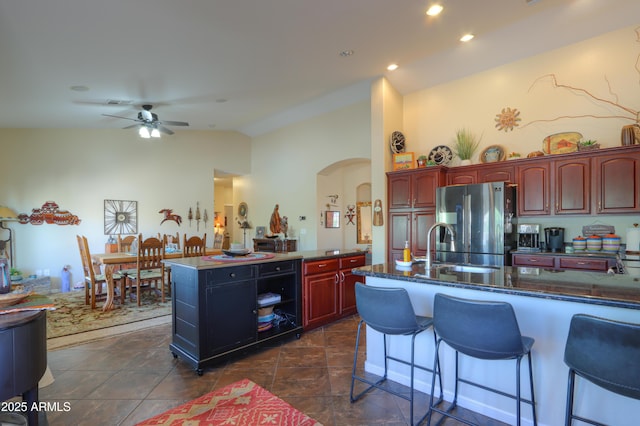 kitchen featuring lofted ceiling, sink, ceiling fan, an island with sink, and stainless steel fridge with ice dispenser