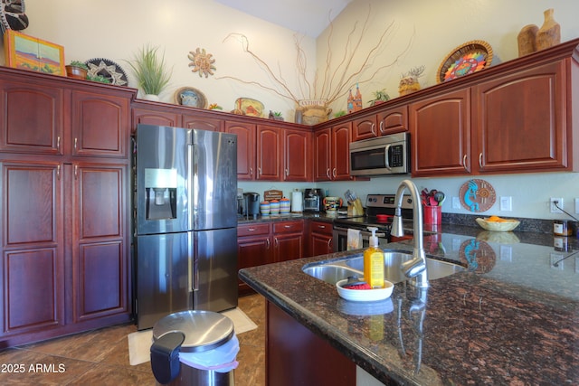 kitchen featuring stainless steel appliances, sink, and dark stone countertops