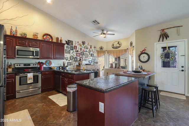 kitchen with sink, a center island, appliances with stainless steel finishes, kitchen peninsula, and ceiling fan