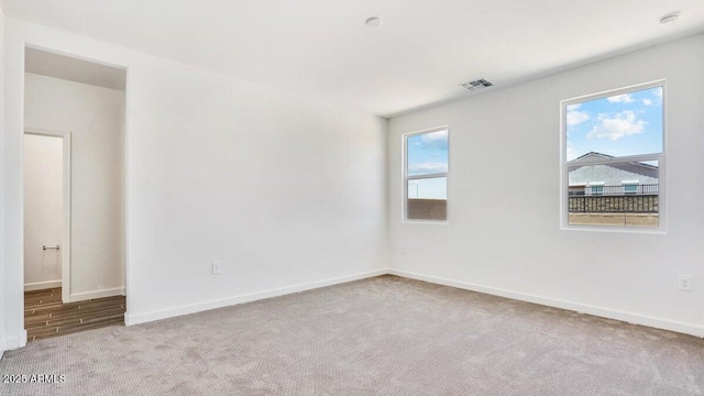 carpeted empty room with visible vents and baseboards