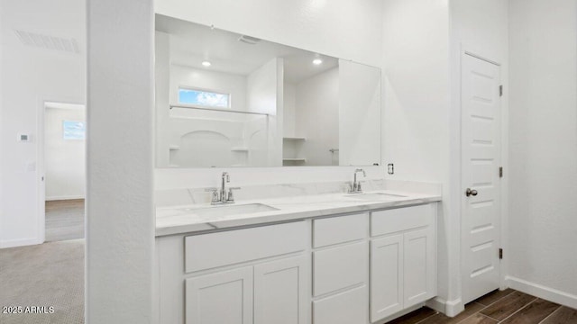 full bathroom featuring a sink, visible vents, wood finished floors, and double vanity