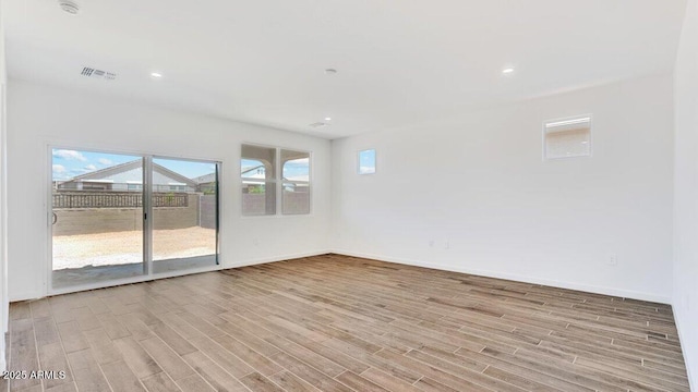 empty room with wood finished floors, visible vents, and baseboards