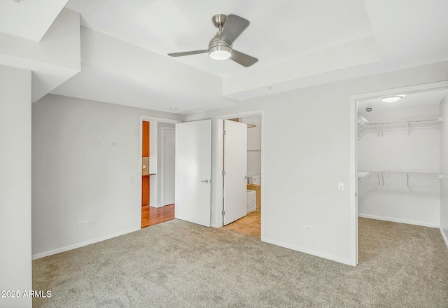 unfurnished bedroom featuring a closet, connected bathroom, carpet, baseboards, and a spacious closet