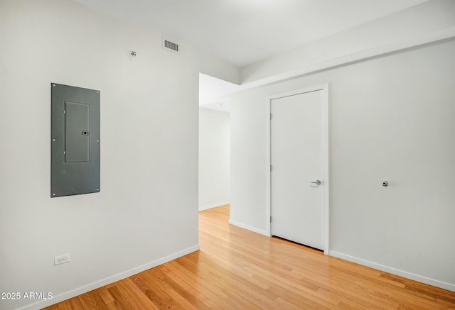 unfurnished room with electric panel, visible vents, baseboards, and light wood-style flooring