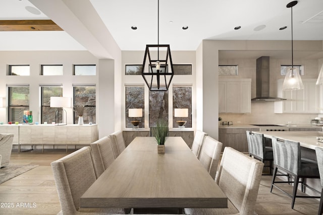 dining space featuring beamed ceiling and light hardwood / wood-style floors