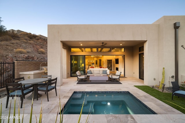 back of house with outdoor lounge area, a patio area, and a pool with hot tub