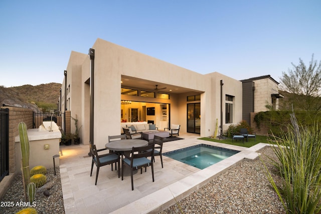 back of property featuring outdoor lounge area, ceiling fan, a pool, a mountain view, and a patio