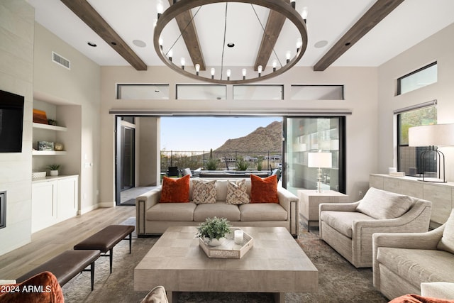 living room with built in shelves, a healthy amount of sunlight, a mountain view, and wood-type flooring