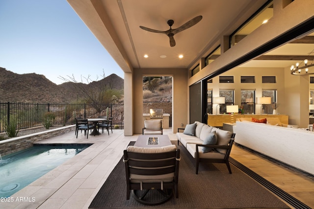 patio terrace at dusk featuring a mountain view, a fenced in pool, an outdoor fire pit, and ceiling fan