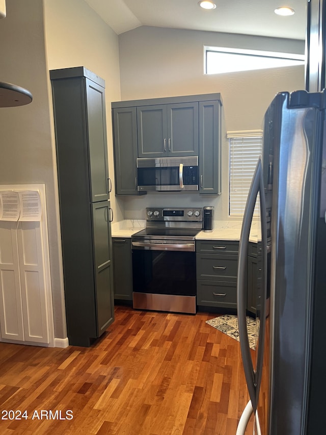 kitchen with hardwood / wood-style floors, lofted ceiling, gray cabinets, and stainless steel appliances