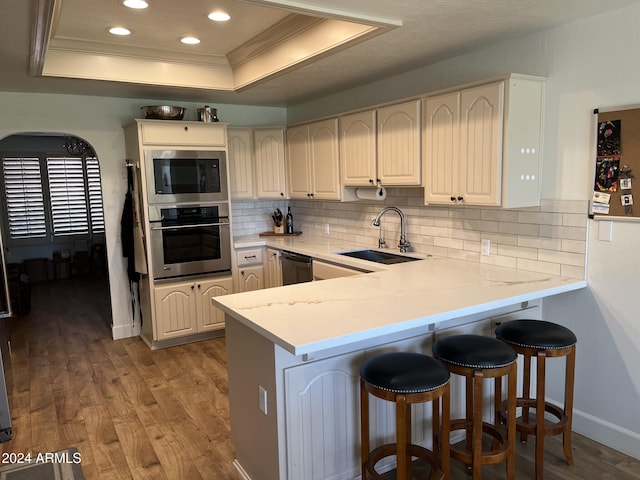 kitchen featuring dishwasher, sink, kitchen peninsula, oven, and a tray ceiling