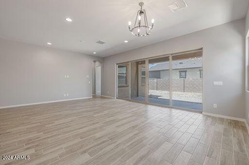 empty room featuring a chandelier and light hardwood / wood-style floors