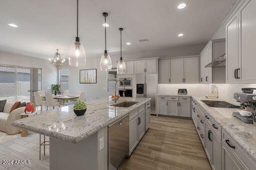 kitchen featuring an island with sink, stainless steel appliances, backsplash, and sink