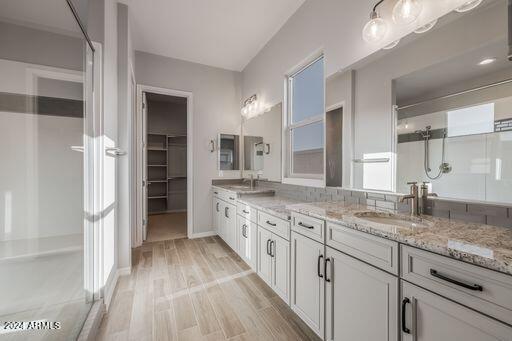 bathroom with wood-type flooring, double sink vanity, and walk in shower