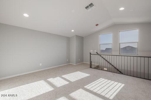 additional living space featuring lofted ceiling and light carpet