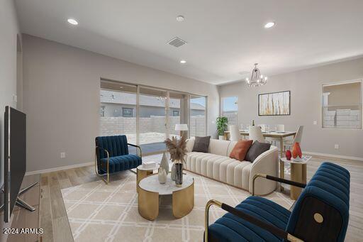 living room featuring plenty of natural light, an inviting chandelier, and light wood-type flooring