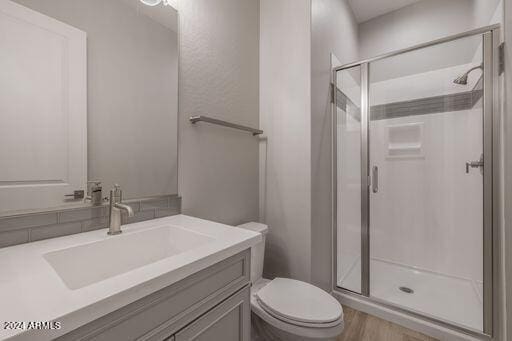 bathroom featuring a shower with shower door, wood-type flooring, vanity, and toilet