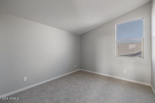 carpeted spare room with vaulted ceiling