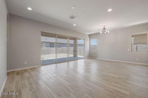 spare room featuring an inviting chandelier and light hardwood / wood-style flooring