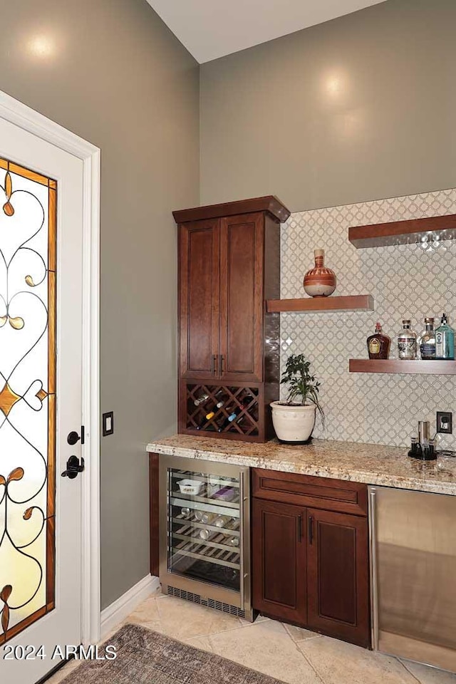 bar featuring wine cooler, light stone countertops, light tile patterned floors, and tasteful backsplash