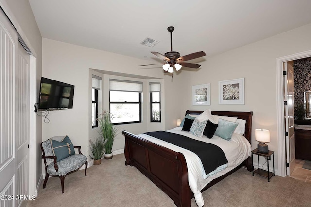 bedroom featuring ceiling fan, a closet, connected bathroom, and light carpet