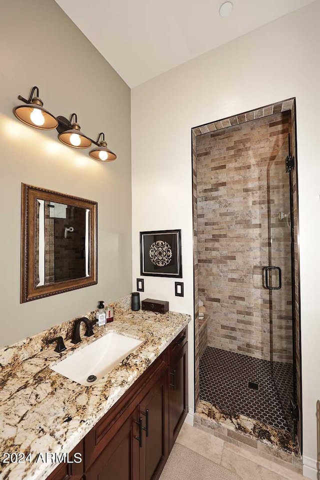 bathroom featuring tile patterned floors, a shower with door, and vanity