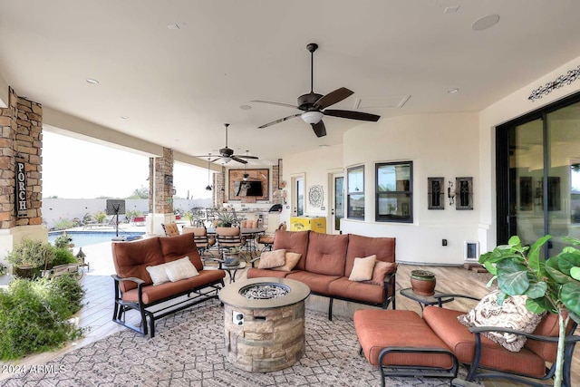 view of patio / terrace featuring ceiling fan and an outdoor living space with a fire pit