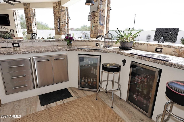 kitchen featuring light hardwood / wood-style flooring, wine cooler, ceiling fan, and stone counters