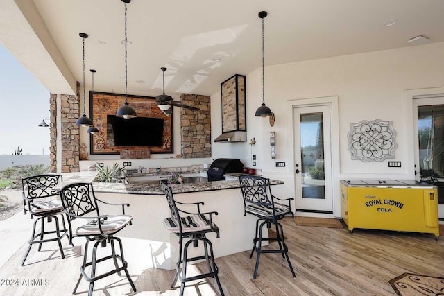 kitchen with a kitchen bar, light wood-type flooring, kitchen peninsula, and a wealth of natural light