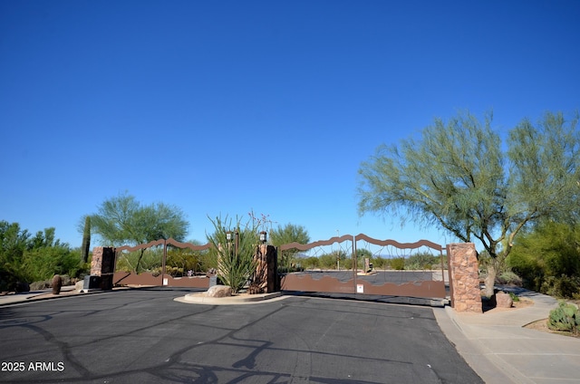 view of street with a gate, a gated entry, curbs, and sidewalks