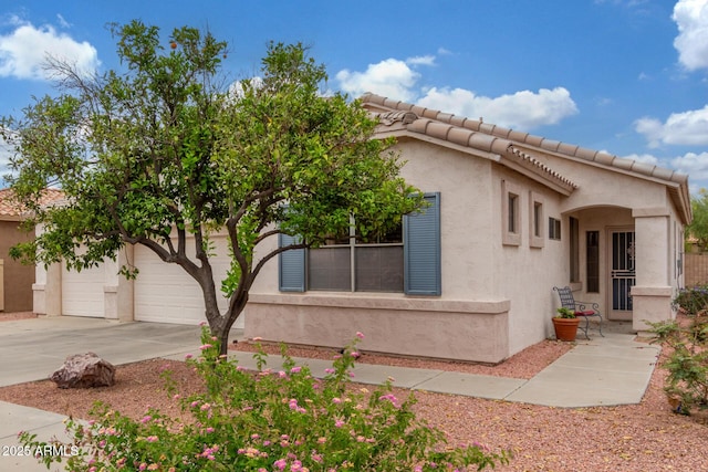 view of front facade with stucco siding, a tile roof, and concrete driveway