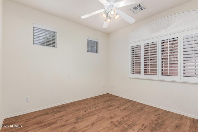 spare room with baseboards, wood finished floors, visible vents, and ceiling fan