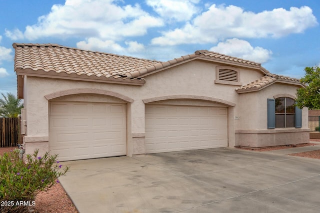 mediterranean / spanish house featuring an attached garage, a tiled roof, stucco siding, and concrete driveway