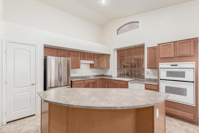 kitchen with high vaulted ceiling, a sink, white appliances, light tile patterned floors, and under cabinet range hood