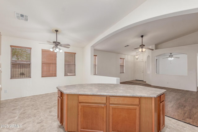 kitchen featuring vaulted ceiling, visible vents, a ceiling fan, arched walkways, and open floor plan